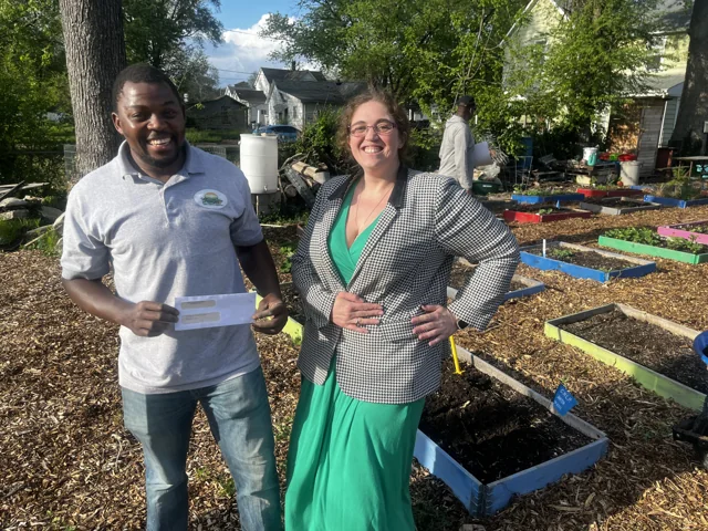 Two people standing together beside raised garden beds