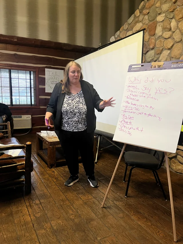 A participant speaking beside a flip chart during a group discussion