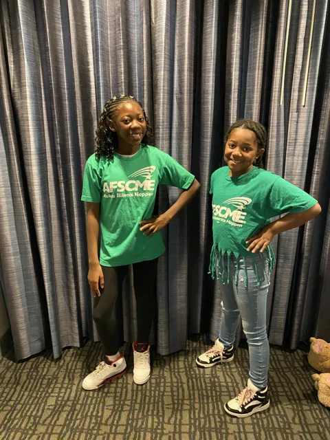 Two people wearing green AFSCME shirts pose together.