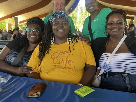 A group of participants smile for photographs at a picnic shelter. Alternate view 2.