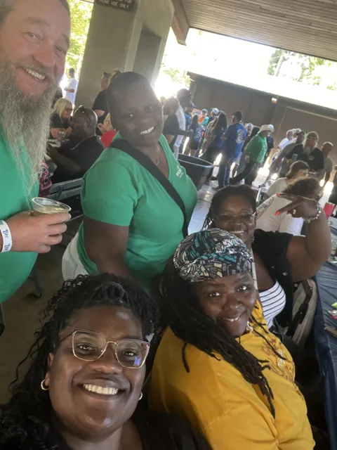 A group of participants smile for photographs at a picnic shelter. Alternate view 4.