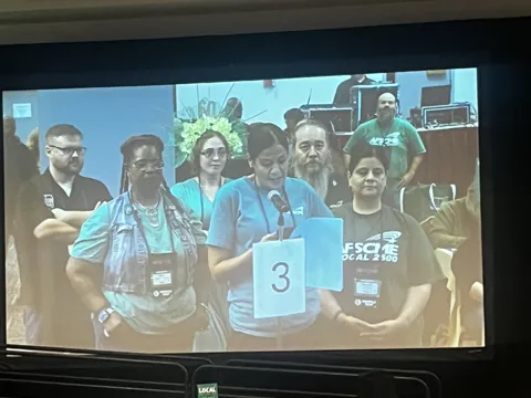A projected photograph shows a group posing behind a table number.