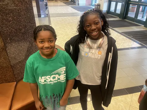 Two young participants, one wearing a green AFSCME shirt, smile together.