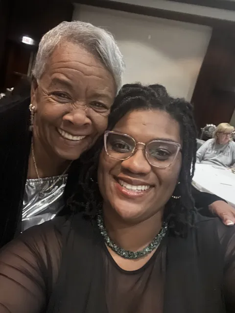 Two smiling participants take a selfie indoors.