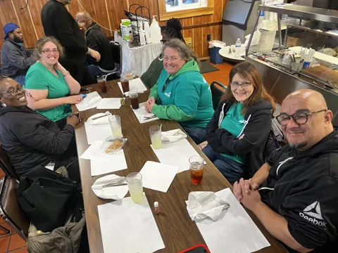 Participants share a meal at a long restaurant table.