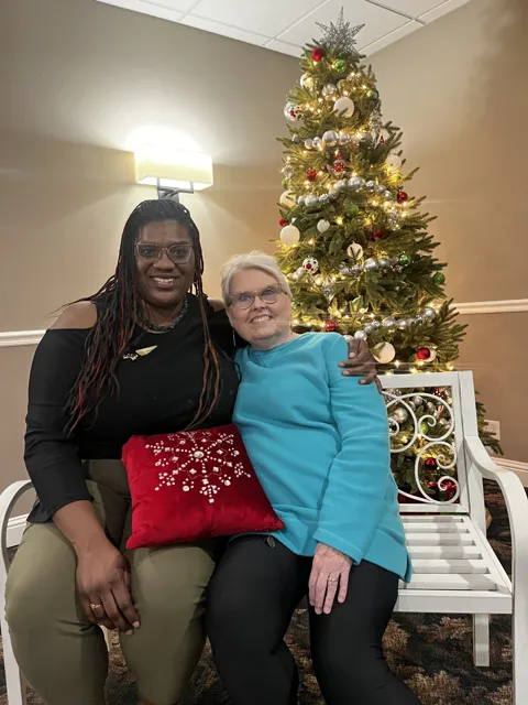 Two people pose beside a decorated Christmas tree. Alternate view 4.