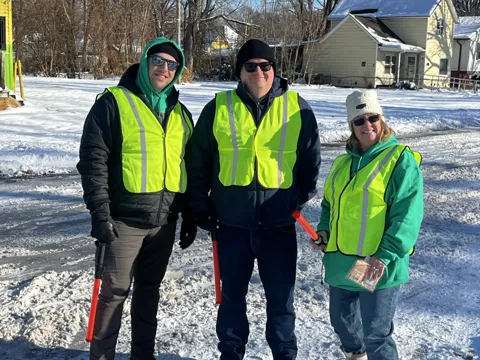 Participants in high-visibility vests pose together outdoors in the snow. Alternate view 2.