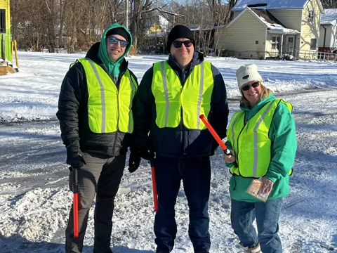Participants in high-visibility vests pose together outdoors in the snow. Alternate view 3.