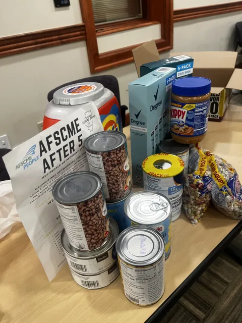 Canned food and packaged groceries collected on a table beside an AFSCME sign.