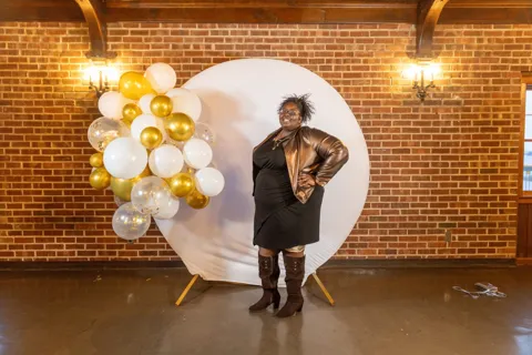 A guest poses in front of the celebration backdrop.