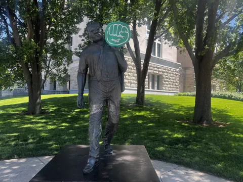 A statue on landscaped grounds with an AFSCME raised-fist symbol nearby.