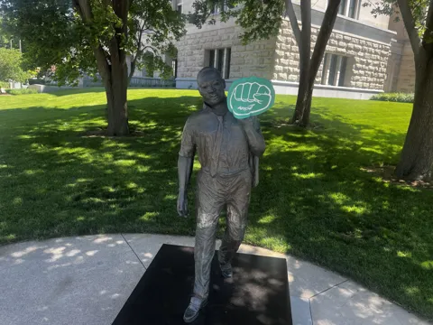 A statue on landscaped grounds with an AFSCME raised-fist symbol nearby. Alternate view 2.