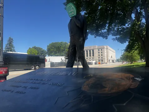 A statue on landscaped grounds with an AFSCME raised-fist symbol nearby. Alternate view 3.