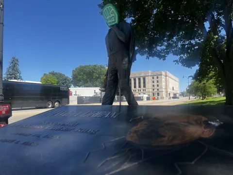 A statue on landscaped grounds with an AFSCME raised-fist symbol nearby. Alternate view 4.