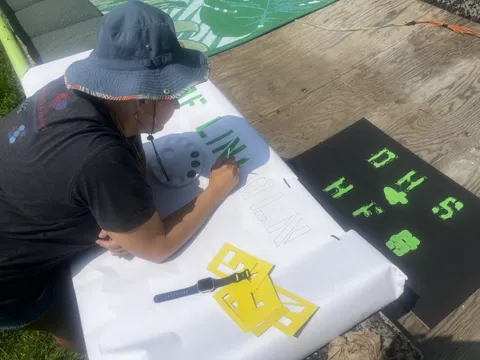 A participant works on a large banner outdoors.