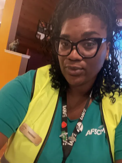A participant wearing glasses, a green AFSCME shirt and a high-visibility vest.