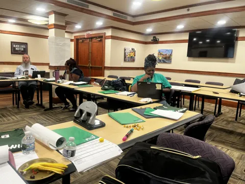 Participants seated around tables during a group discussion and presentation.